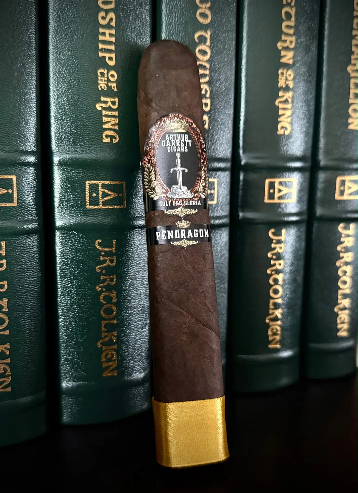 A cigar resting against dark green books with gold lettering